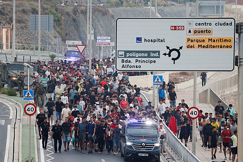 Police officers and Spanish soldiers escort a big group of migrants to the border to take them out of Spain, after mass crossings of migrants on foot and by sea from Morocco into Spanish territory, in Ceuta, Spain, August 1, 2026.