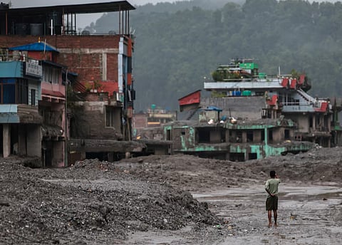 A man takes pictures in front of damaged buildings after flash floods and a mudslide, in Trishuli, Nuwakot district, Nepal, August 29, 2026. 