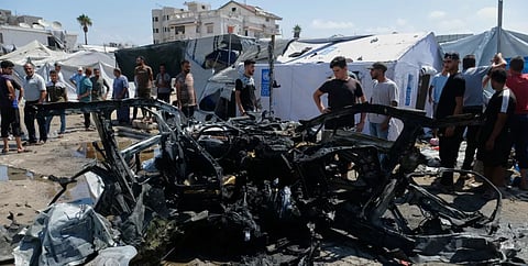 Palestinians gather around a destroyed vehicle on a street following an Israeli military strike in Gaza City, Tuesday, Sept. 1, 2026.