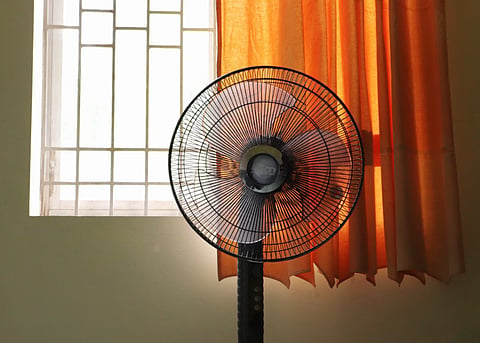 Representational image of a stand-fan by the window of a room on a hot day.