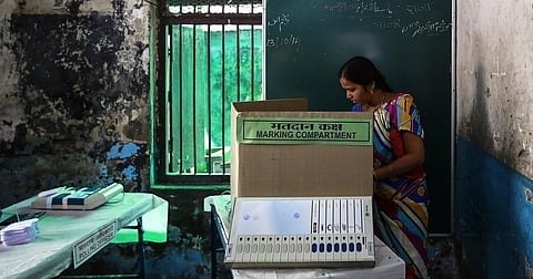 This image shows a woman casting her vote at a polling station in Mumbai during the Maharashtra state elections on October 15, 2014.