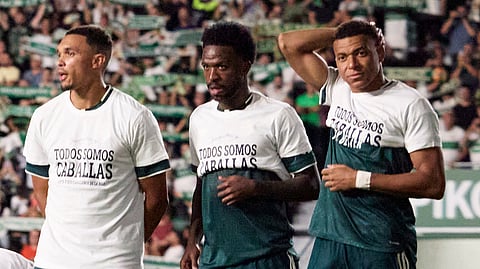 Real Madrid's Kylian Mbappe (R) and Vinicius Junior roll up their shirts to display a slogan in solidarity with the people of Ceuta before the match.