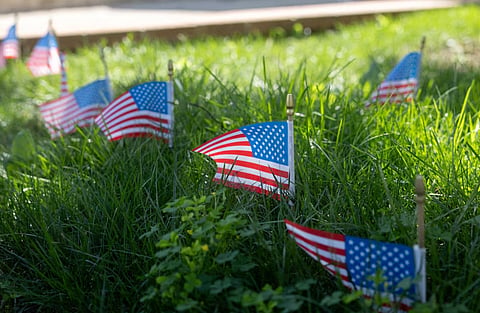 A neighbor places flags in their yard in support of the family of fallen U.S. soldier Sgt. Angel S. Rampersad in New York City, US, July 23, 2026.