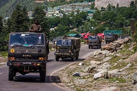 An Indian army convoy driving towards Leh on a highway bordering China. 
