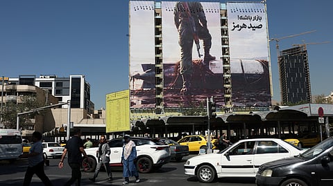 People walk past a billboard with a picture of an unmanned US submersible, in Tehran, Iran, September 23, 2026.