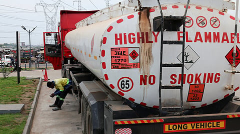 A worker waits as an oil tanker truck prepares to offload at a fuel station in Tema, Ghana, April 1, 2026.