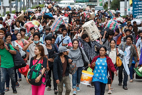 Cambodian migrant workers carry their belongings as they walk to cross the border at Aranyaprathet, Thailand, on June 15, 2014. 