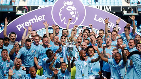 Manchester City manager Pep Guardiola celebrates with the trophy, players and staff after winning the Premier League.