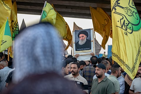 A demonstrator holds a portrait of Iraq's top Shiite cleric, Grand Ayatollah Ali al-Sistani, during a protest against the suspension of flights between Iraq and Iran outside Najaf International Airport in Najaf, Iraq, Monday, Sept 28, 2026.