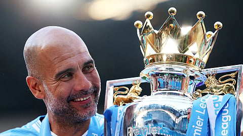 Former Manchester City manager Pep Guardiola celebrates with the trophy after winning the Premier League.