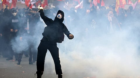 A masked protester throws an object amid clashes with French police during a demonstration by high school and university students on Tuesday.