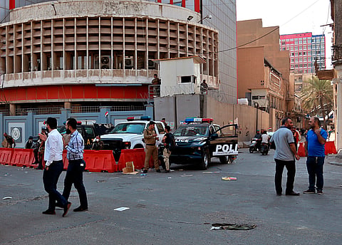 Employees of Iraq central bank, in the background, leave while security forces stand guard in central Baghdad, Iraq, Nov 6, 2019.