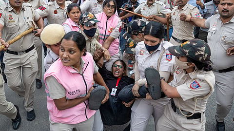 Security personnel and police detain a journalist during a protest by the Cockroach Janta Party (CJP) seeking the resignation of India's Chief Election Commissioner Gyanesh Kumar, near the protest site in New Delhi, India, October 11, 2026. 