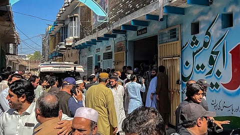 Residents gather during a search operation after a roof collapsed at a school in Peshawar on October 15, 2026. 