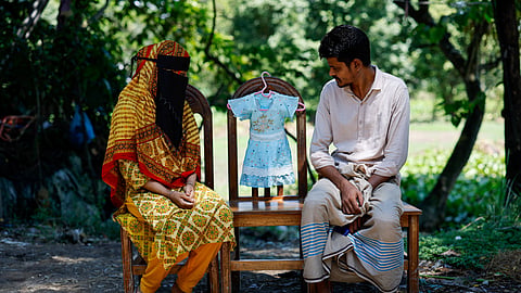 Nadia Akter Manna and Humayun Rashid, 30, look at a dress belonging to their nine-month-old daughter, Labiba Akter, who died during a recent deadly measles outbreak, as they pose for a photograph in Sunamganj, Bangladesh, September 13, 2026. 
