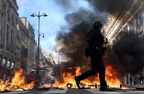 French riot police walk past burning objects in a street amid clashes with protesters in Paris as part of nationwide protests against the cost of living and rising fuel prices called by the "Yellow Vests" movement, joined by French high school and university students, teachers and parents demanding better school conditions and government action, as well as labour unions, workers, farmers and retirees, France, October 17, 2026.