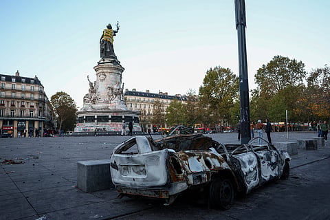 A destroyed car near the Marianne statue at the Place de la Republique, with a yellow vest put on it, the day after clashes during a national day of demonstrations against the cost of living and rising fuel prices, in Paris, France, October 18, 2026. The back of the vest reads: 'In 1961 the police drowns Algerian women'.