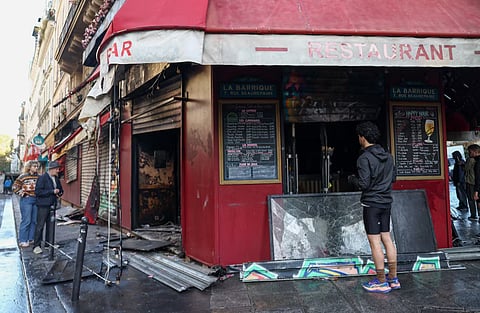 People inspect the damaged restaurant La Barrique, the day after clashes during a national day of demonstrations against the cost of living and rising fuel prices, near the Place de la Republique in Paris, France, October 18, 2026.