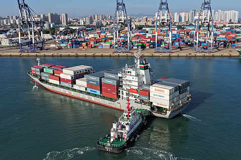 A tugboat pushes a container ship to a port in Yantai, eastern China's Shandong province on Oct 14, 2026. 