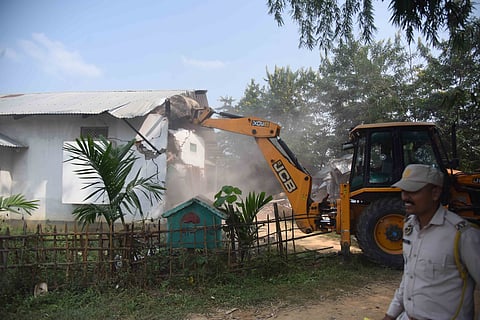 An Assam forest department official uses an excavator to demolish illegal constructions inside the Borpani Reserve Forest in Nagaon District, Assam, India, on October 17, 2026.