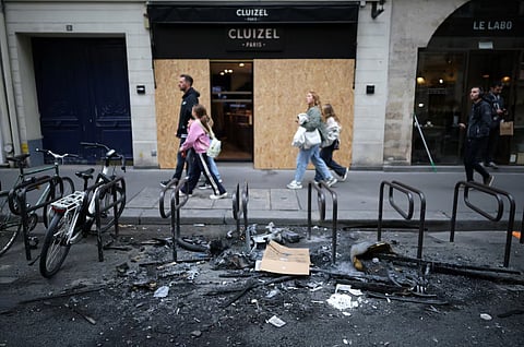 People walk past a shop with its display windows protected by wooden panels days after nationwide protests against the cost of living and rising fuel prices called by the "Yellow Vests" movement and ahead of a second round of demonstrations in Paris, France, October 21, 2026.