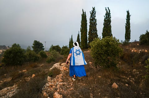 A Jewish settler walks towards olive trees owned by Palestinians due to be harvested, near the Israeli settlement Neve Daniel, in the Israeli-occupied West Bank, October 12, 2026. 
