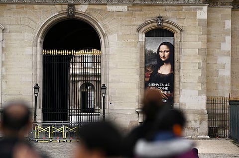 People stand in front of a poster depicting "Mona Lisa" (La Joconde) in front of the Louvre Museum, which is closed all day due to the fears of renewed turmoil in Paris ahead of nationwide protests called by the "Yellow Vests" movement joined by French high school and university students, against the cost of living and rising fuel prices in France, October 24, 2026.