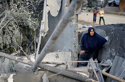 A Palestinian woman inspects the site of a house targeted by an Israeli airstrike after the Israeli military warned the residents of the house to evacuate on Thursday, in Nuseirat in the central Gaza Strip, October 23, 2026. 