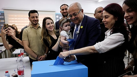 Palestinian candidate Ahmad Tibi of the Joint List party with his family votes during the national election, in the Arab village of Taibe, northern Israel, October 27, 2026.
