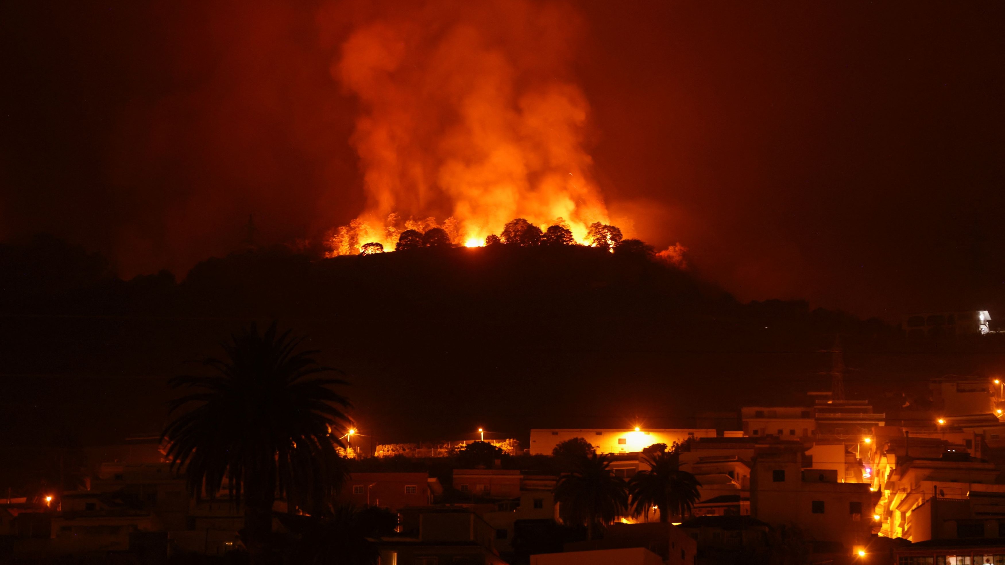 A view shows a fire over the mountains near empty houses after the evacuation in different villages in the north, as wildfires rage out of control on the island of Tenerife, Canary Islands, Spain August 20, 2023.