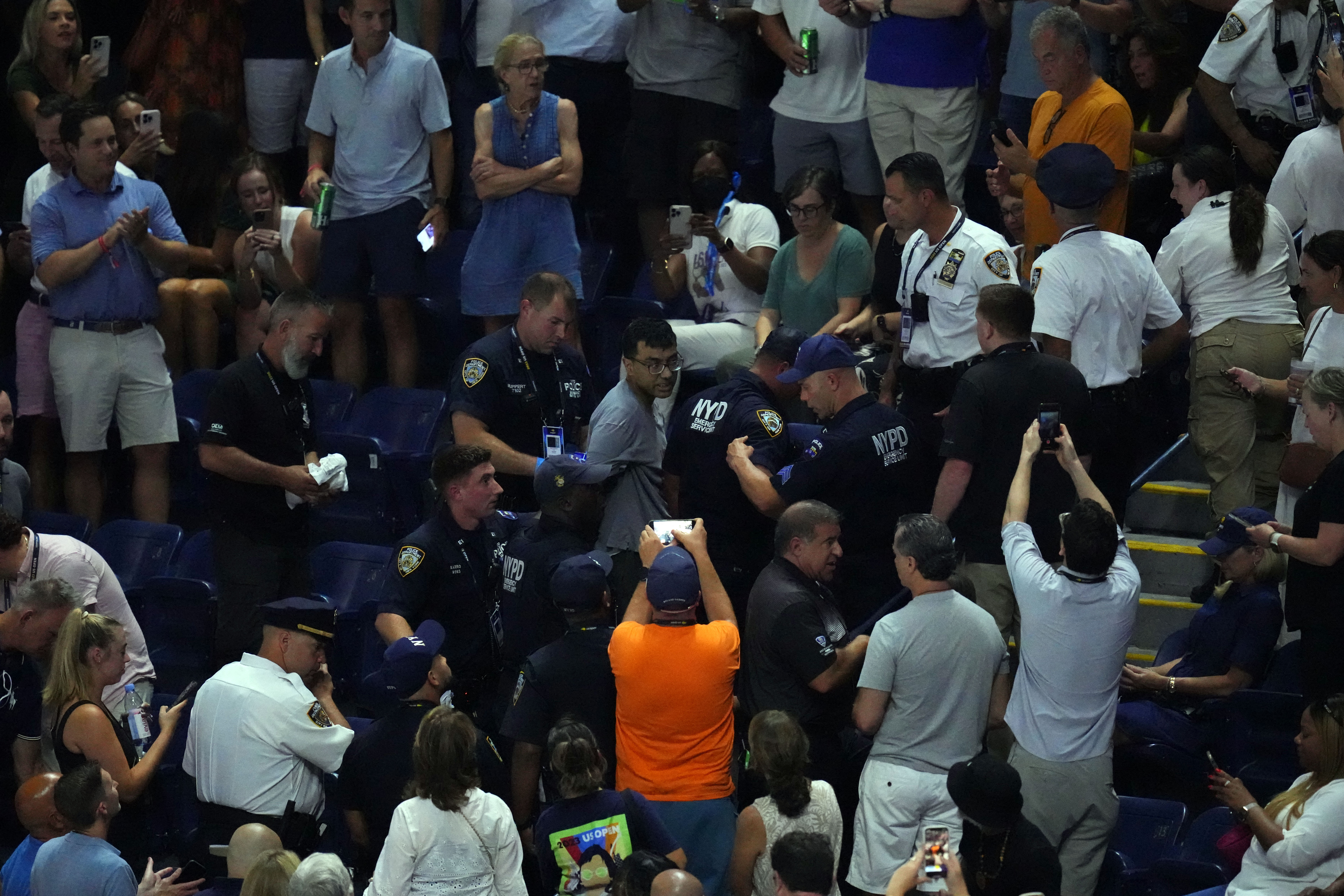 Police officers remove a climate change protester as play is suspended in the second set of the women's semifinal between Coco Gauff of the United States and Karolina Muchova of Czech Republic on day eleven of the 2023 US Open tennis tournament at USTA Billie Jean King National Tennis Center.