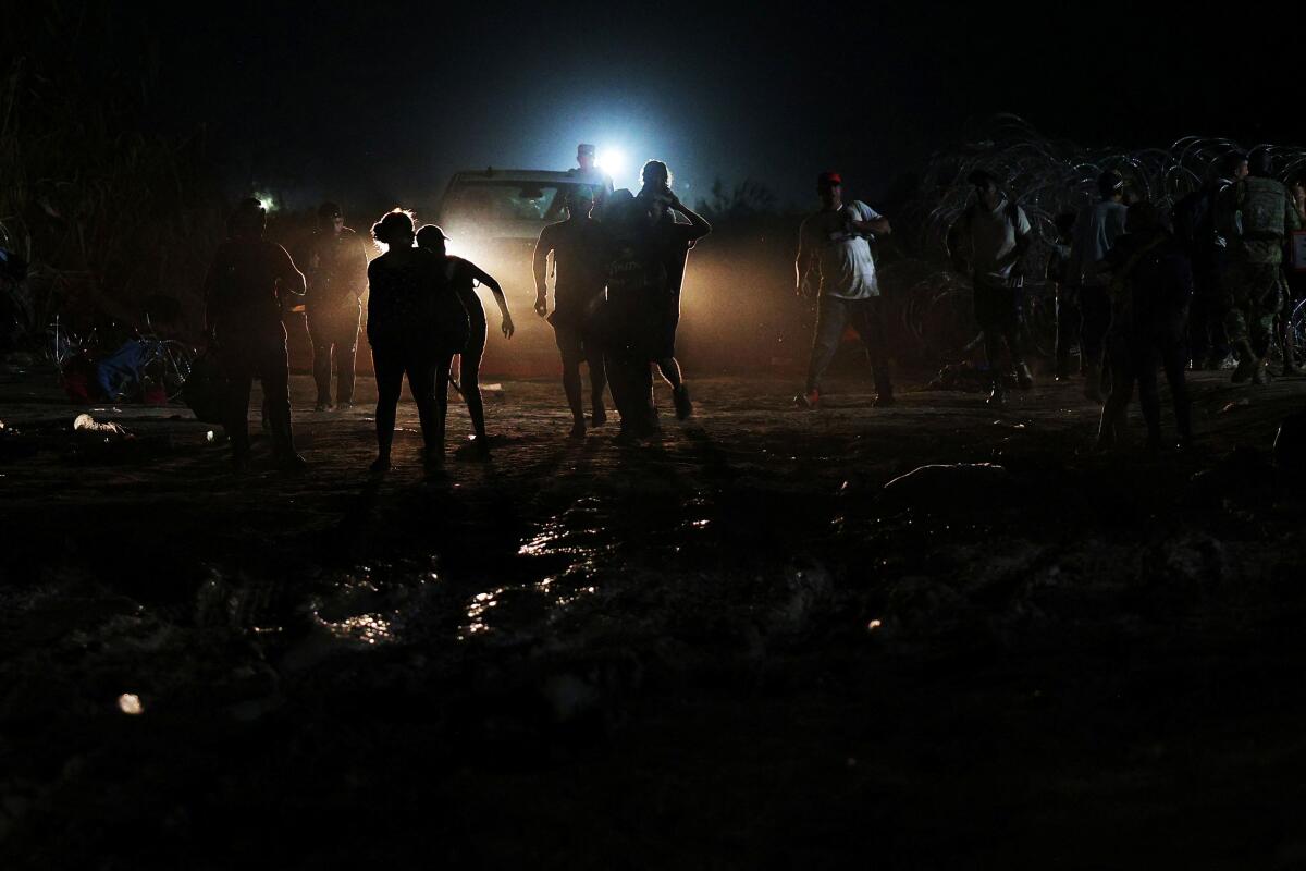 Members of a large group of migrants from Venezuela, who crossed the Rio Grande after sundown, climb through razor wire to finish their trip into the United States in Eagle Pass, Texas.