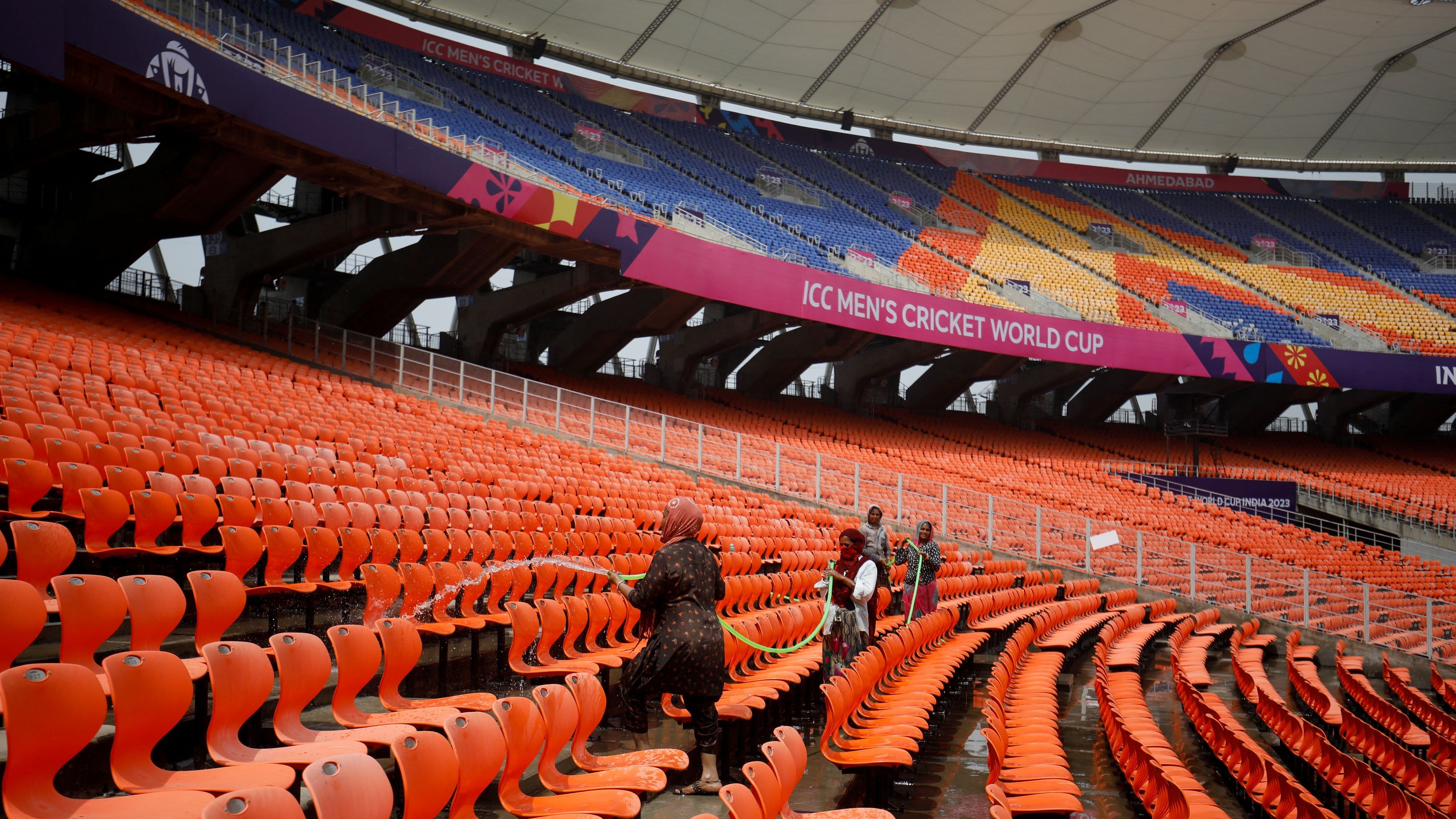 Workers clean the seats in the stands at Narendra Modi Stadium, ahead of ICC Men's Cricket World Cup match, in Ahmedabad. 