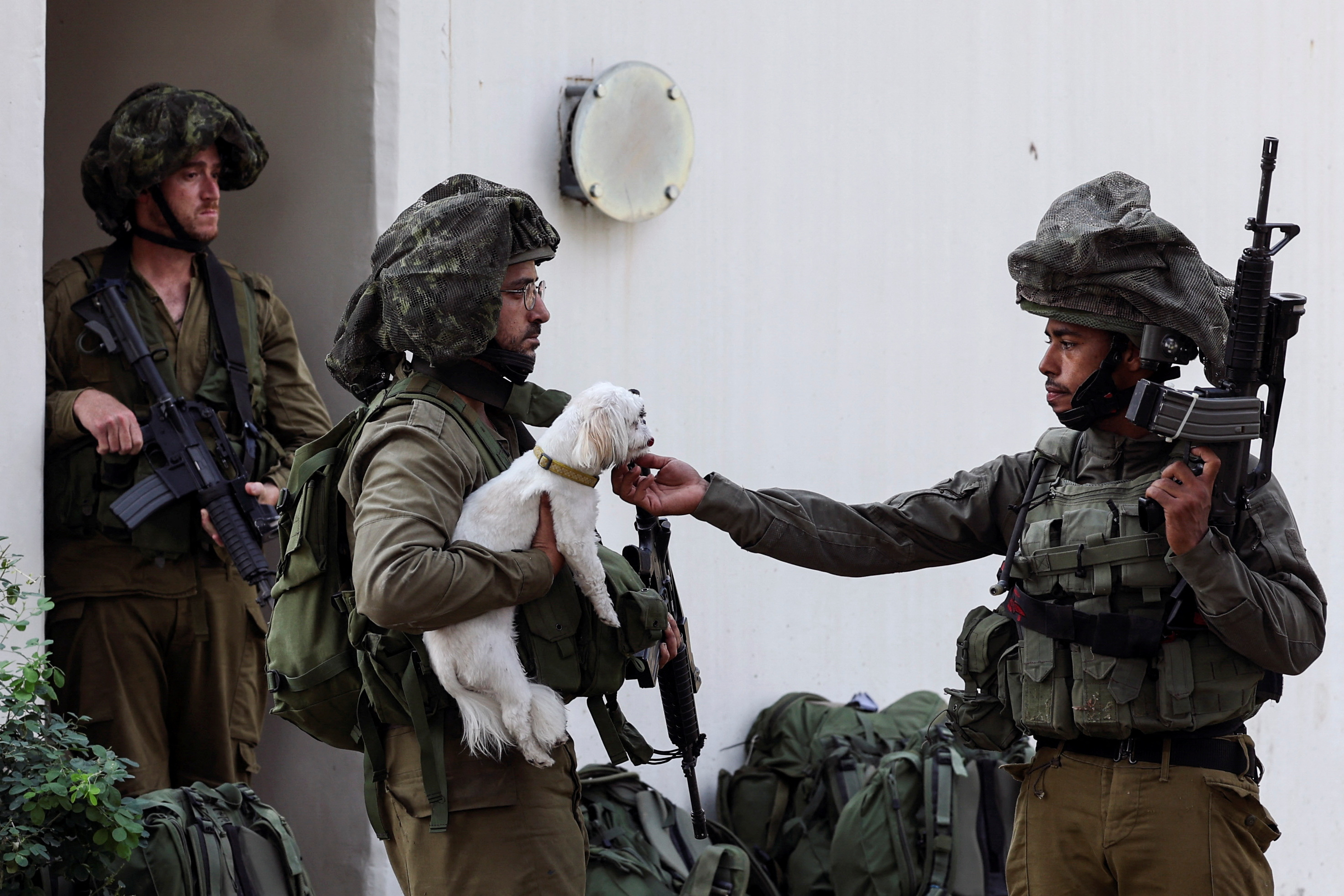 An Israeli soldier pets a rescued dog near a bomb shelter in Kibbutz Kfar Aza, in southern Israel.