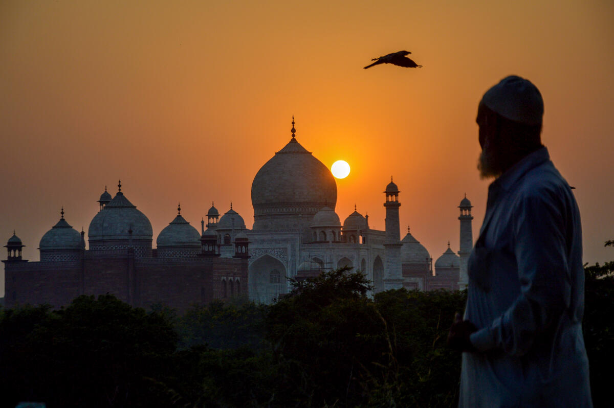 The sun sets in the sky above the Taj Mahal, in Agra.