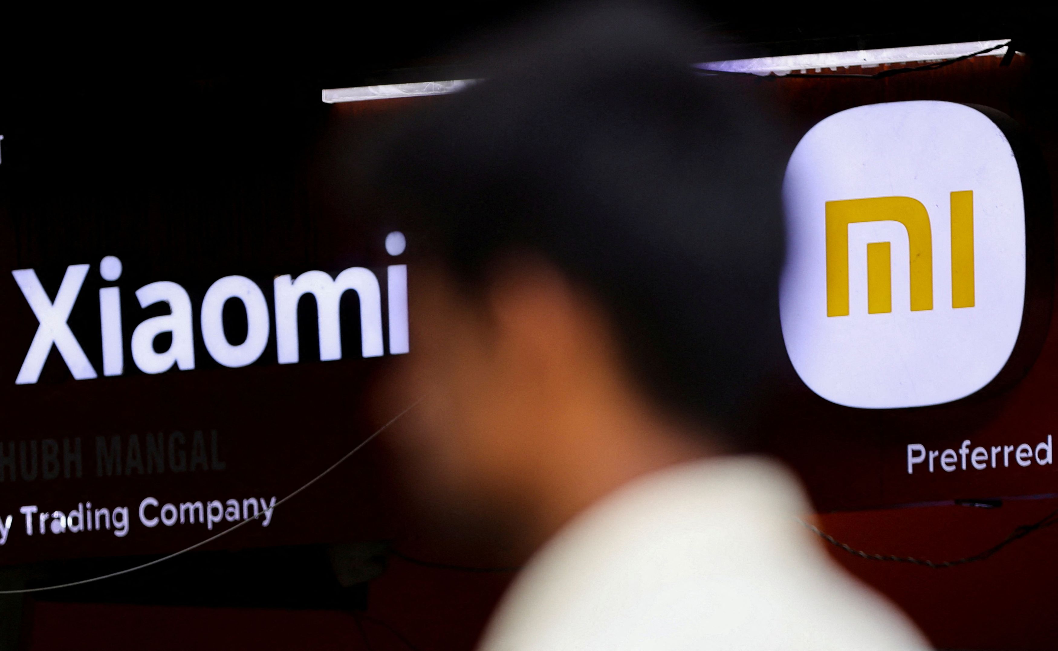 FILE PHOTO: A man walks past a logo of Xiaomi, a Chinese manufacturer of consumer electronics, outside a shop in Mumbai, India.