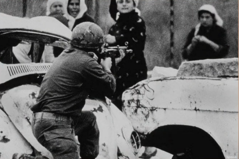 An Israeli soldier points a  rifle at a Palestinian woman holding a rock during a demonstration in Gaza, February 29, 1988.