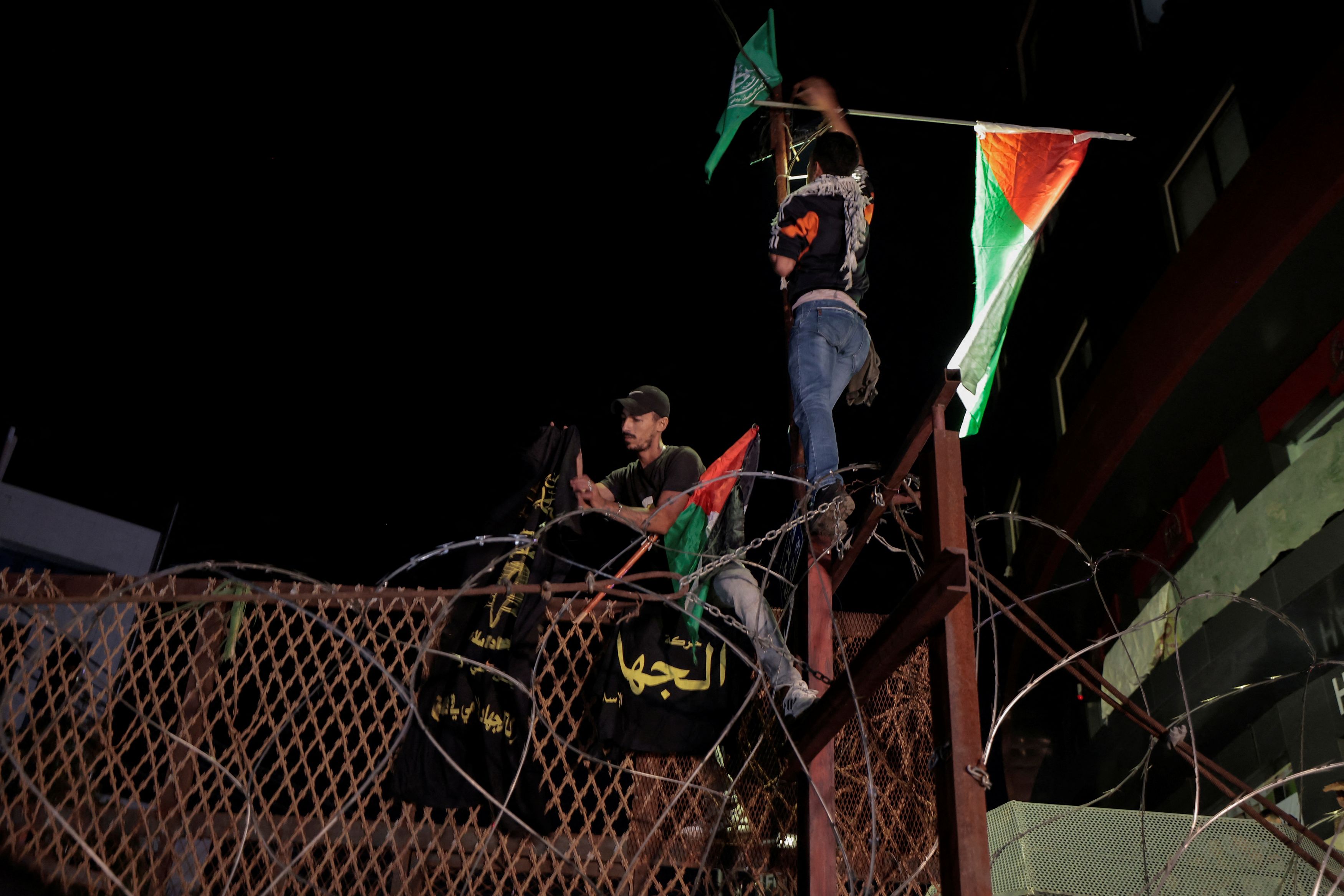Lebanese protesters hang the Palestinian flag  and signs on fence of  the US embassy fence after hundreds of Palestinians were killed in a blast at Al-Ahli hospital in Gaza that Israeli and Palestinian officials blamed on each other, in front of the US embassy in Beirut, Lebanon October 17, 2023.  the sign reads : "Jihad ". 