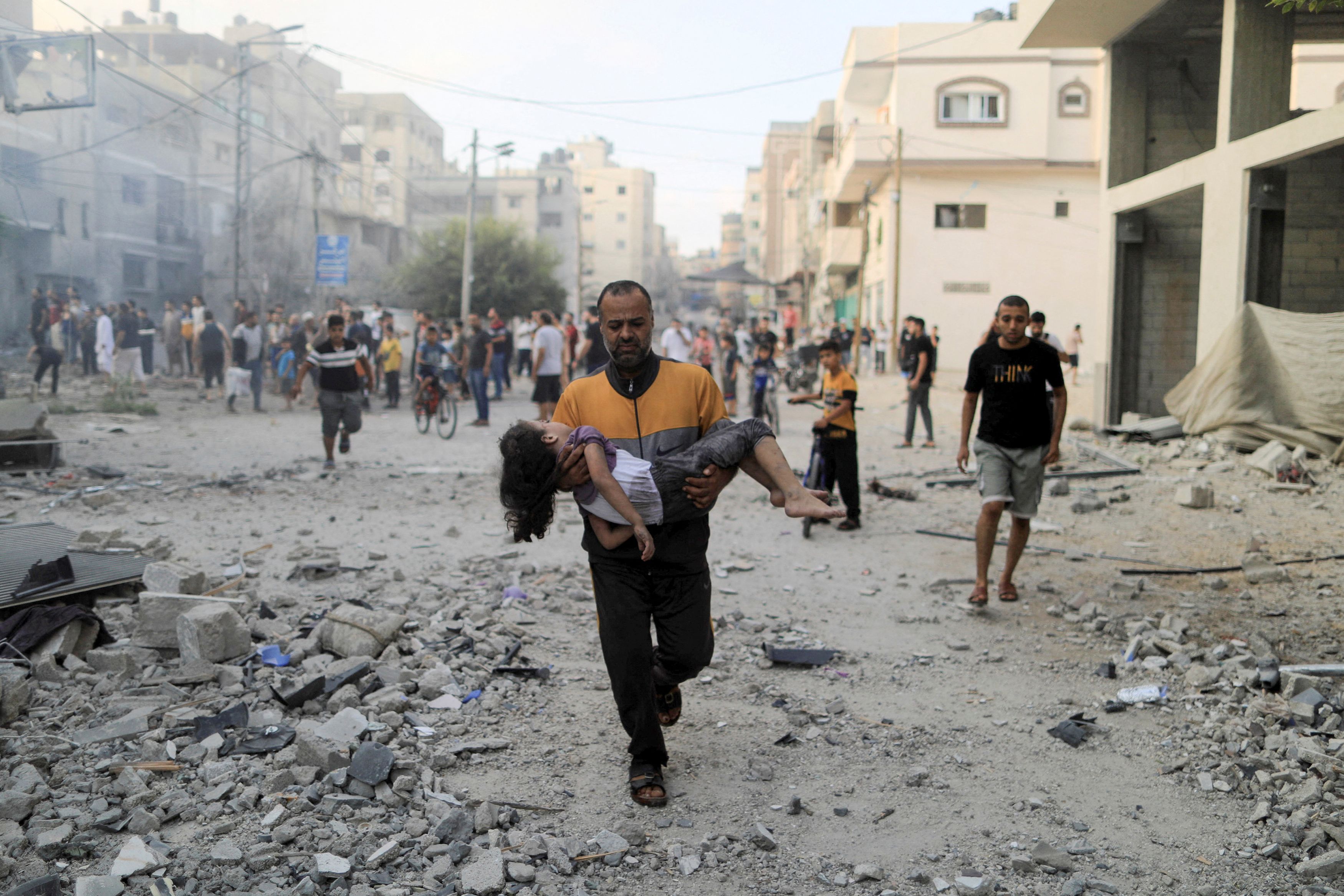 A Palestinian man carries a wounded girl at the site of Israeli strikes, in Khan Younis in the southern Gaza Strip October 14, 2023.