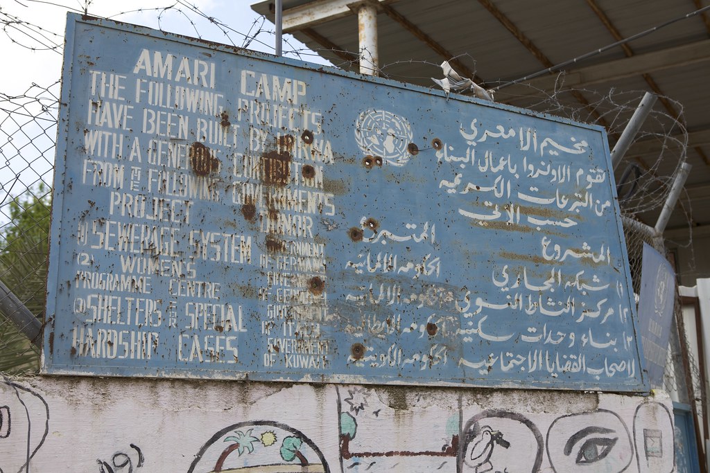 Gunshots fired during the Second Intifada shatter the signboard of a UNWRA school in Al-Am'ary Refugee Camp, West Bank, undated.