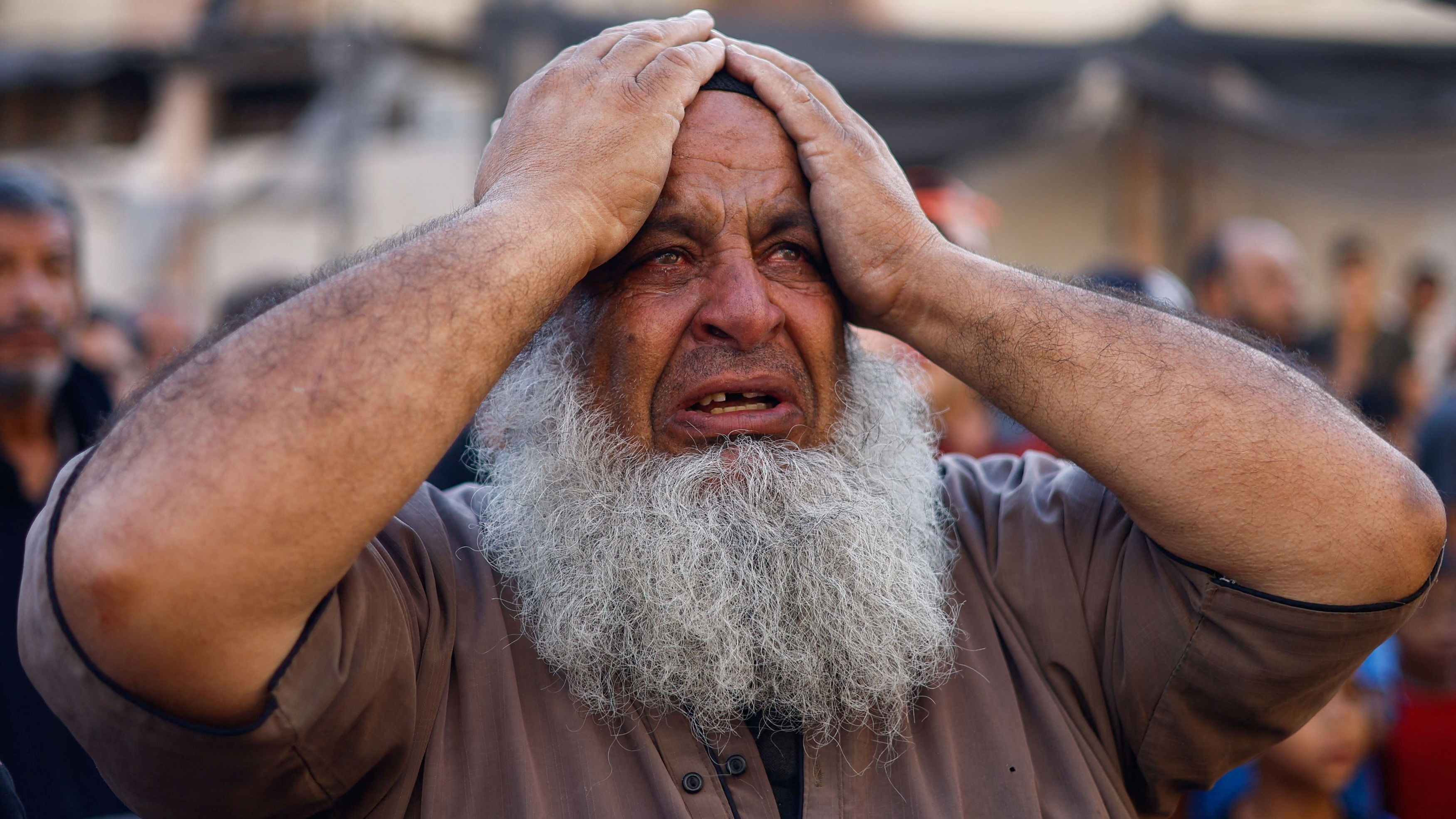 A Palestinian man reacts as people search for casualties under the rubble of a building destroyed by Israeli strikes in Khan Younis in the southern Gaza Strip, October 17, 2023. 