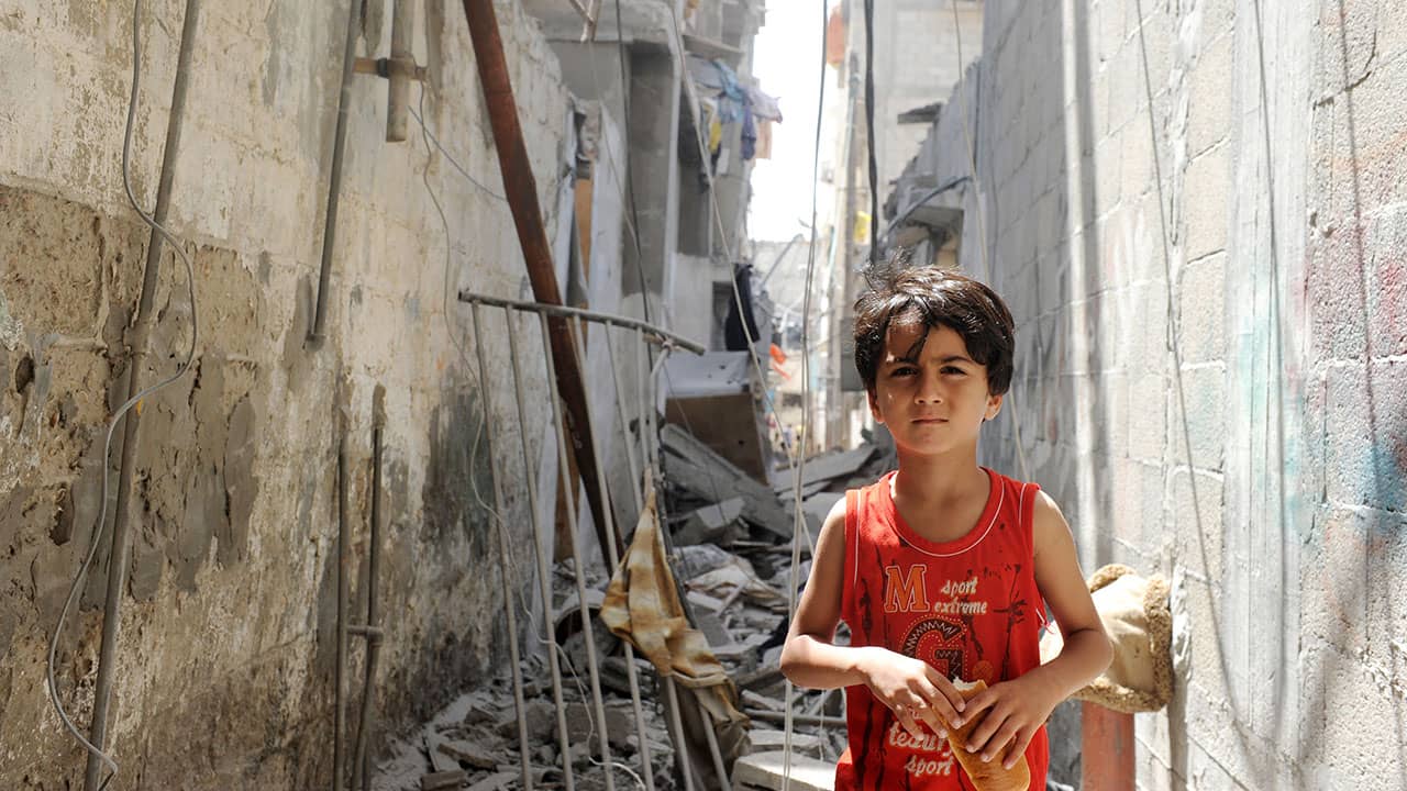 A young Palestinian boy walks through the remains of a house targeted by an Israeli air strike near a beach refugee camp west of Gaza City, 2014.