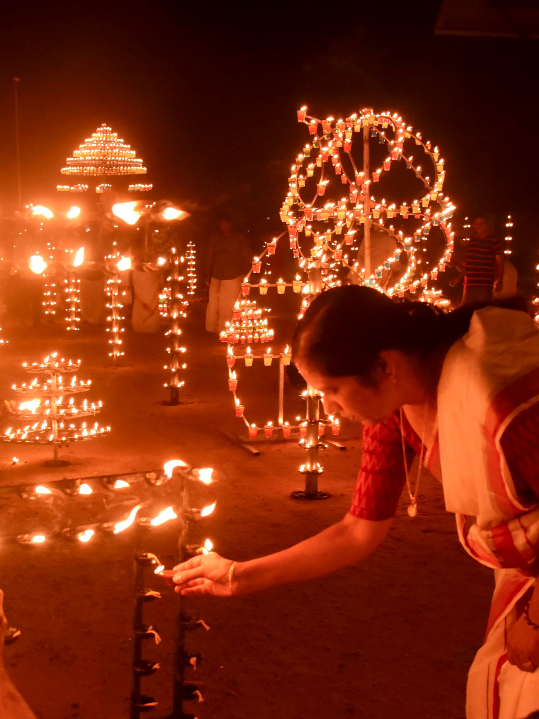 A woman lights a lamp during Diwali celebration at Manjummmel Sri Krishna Temple, in Kochi.