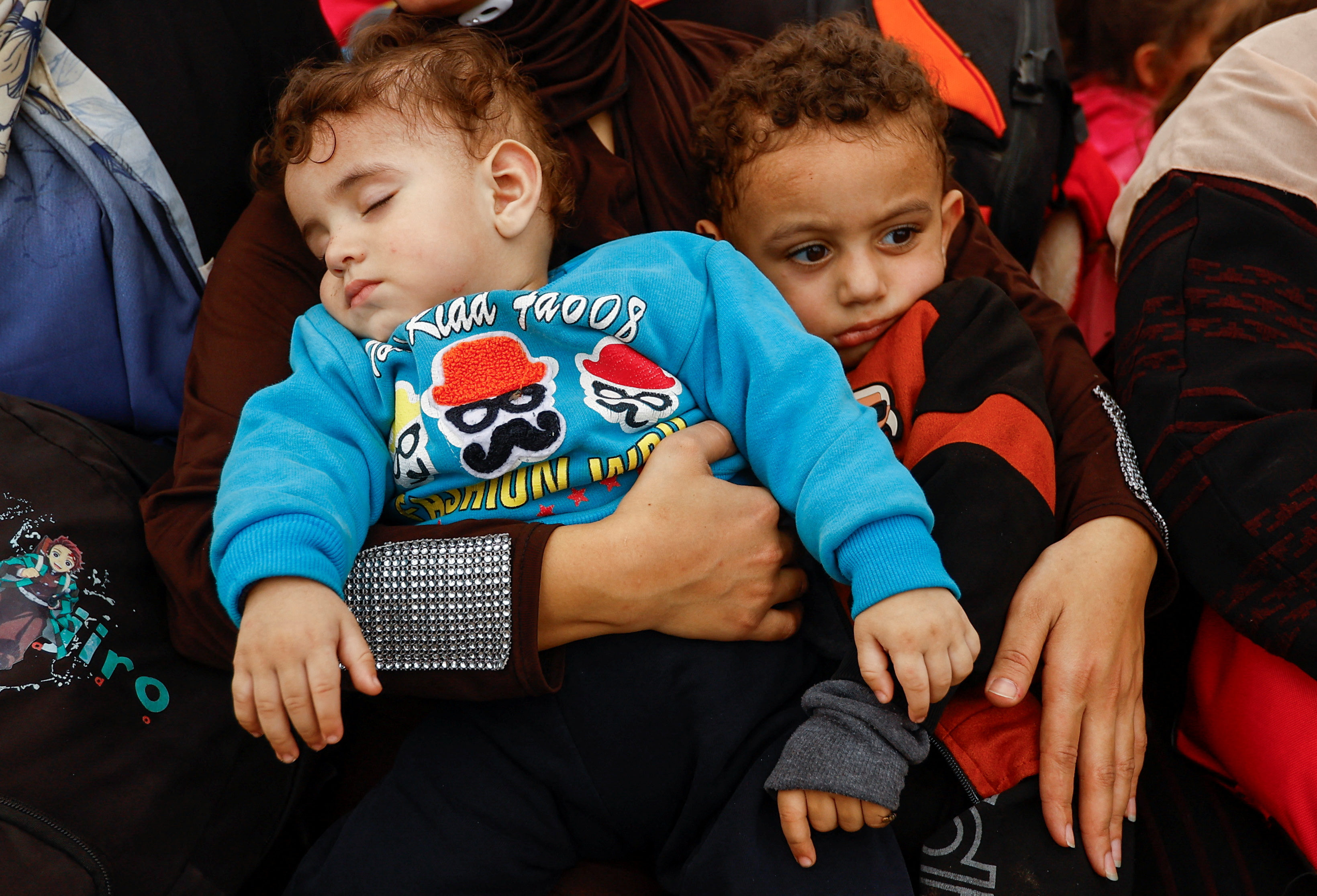 A woman holds her children, as Palestinians flee north Gaza to move southward, as Israeli tanks roll deeper into the enclave, amid the ongoing conflict between Israel and Hamas, in the central Gaza Strip November 12, 2023. 