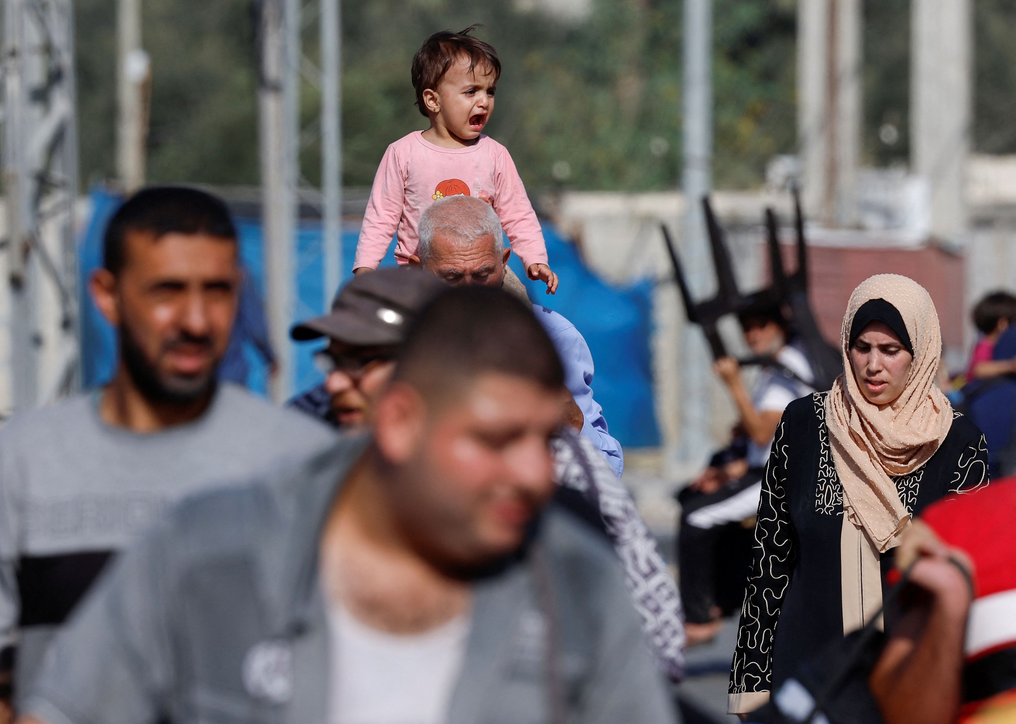 A man carries a child on his shoulders, as Palestinians fleeing north Gaza head towards the south, amid the ongoing conflict between Israel and Palestinian Islamist group Hamas, in the central Gaza Strip, November 9, 2023. 