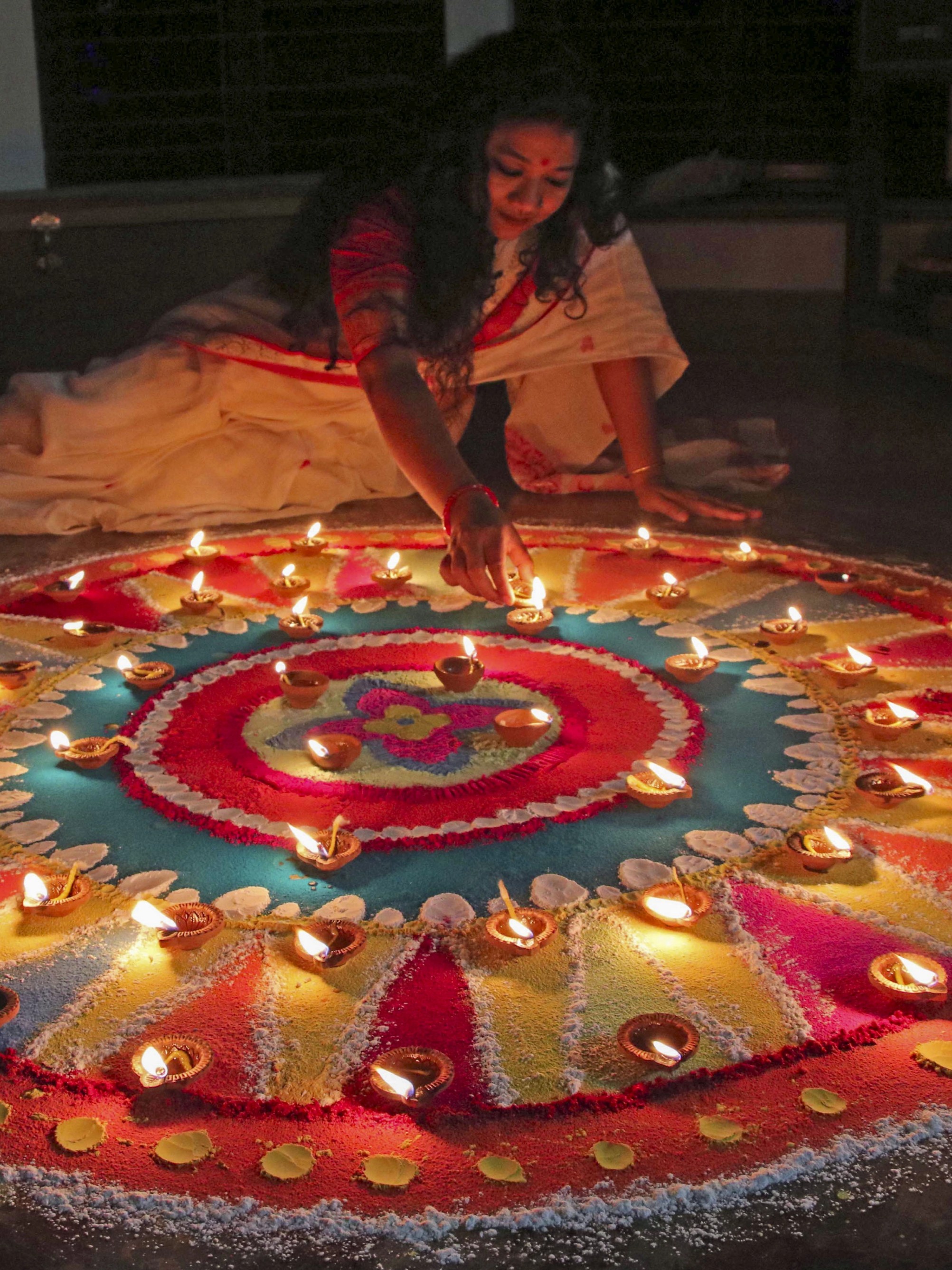 A young woman decorates a 'rangoli' with earthern lamps on Diwali festival, at Santiniketan in Birbhum, West Bengal.