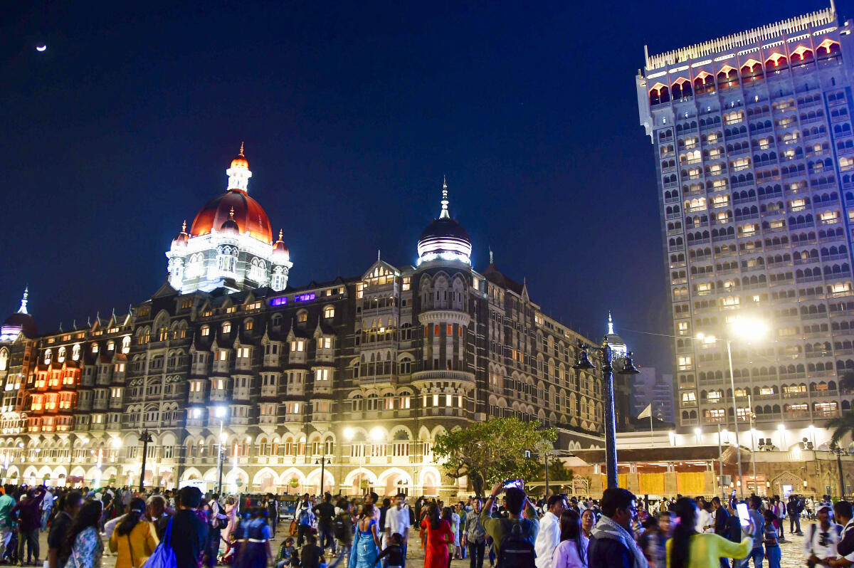 People outside the illuminated Taj Mahal Palace during the celebration of its 120th year, at Taj Mahal Palace in Mumbai.