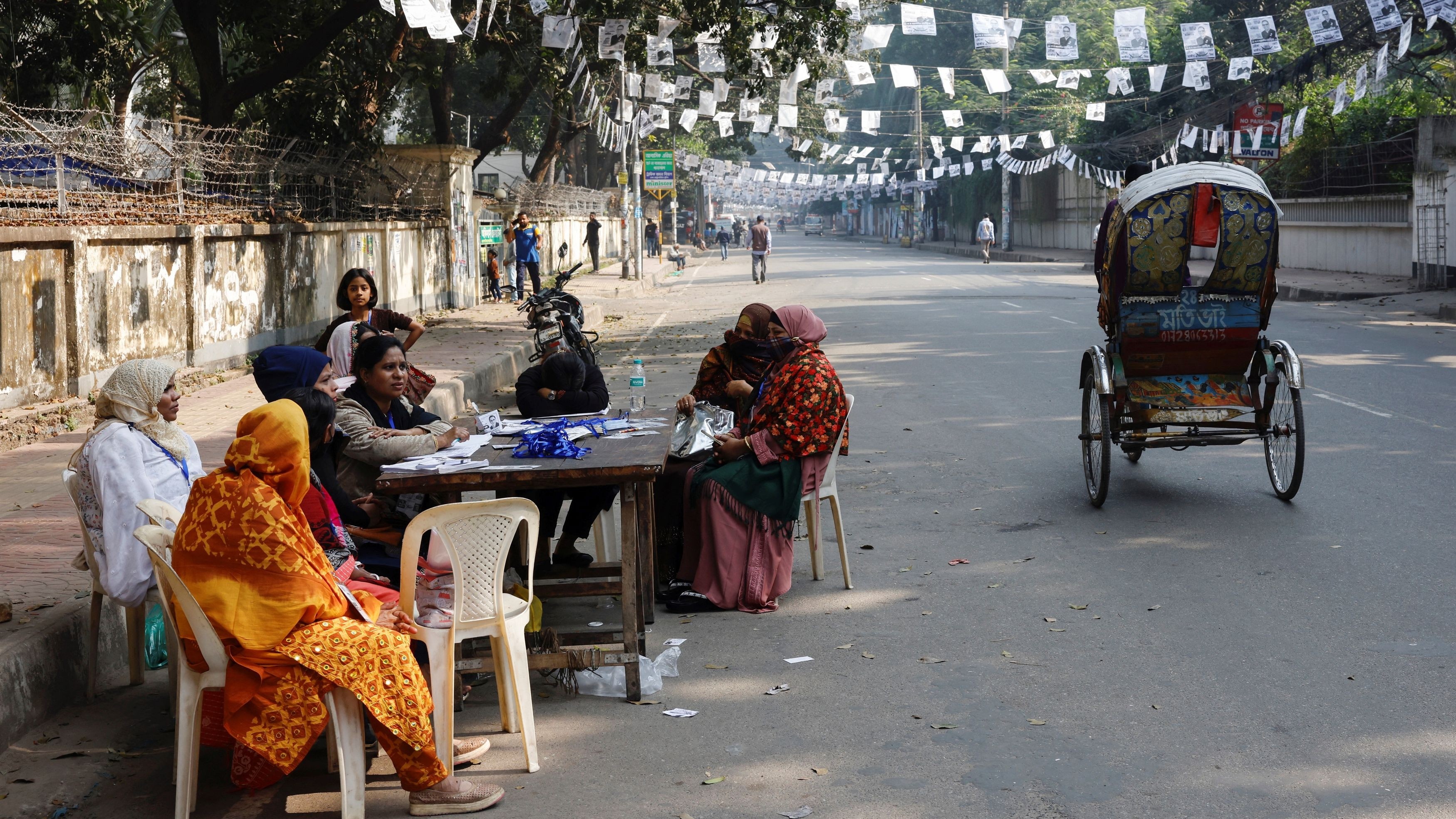 Polling agents sit idly at the Viqarunnisa Noon School and College polling station at midday due to a lack of voters, during the 12th general election in Dhaka, Bangladesh, January 7, 2024.