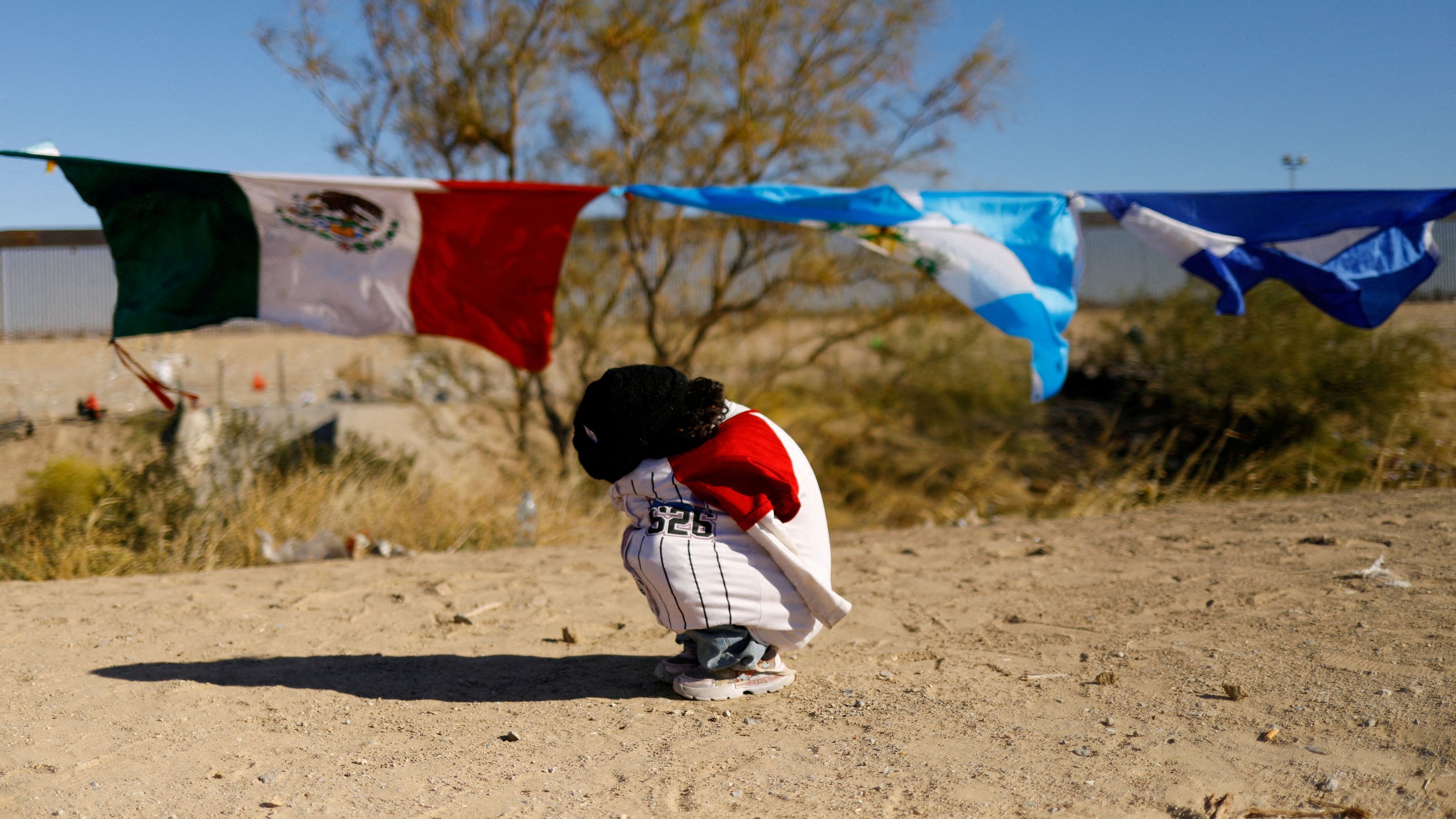 Helen, a 5-year-old migrant girl from Venezuela traveling with her family and seeking asylum in the United States, covers herself from the cold during the celebration of Epiphany Day, at the border between Mexico and the United States, in Ciudad Juarez, Mexico, January 6, 2024.