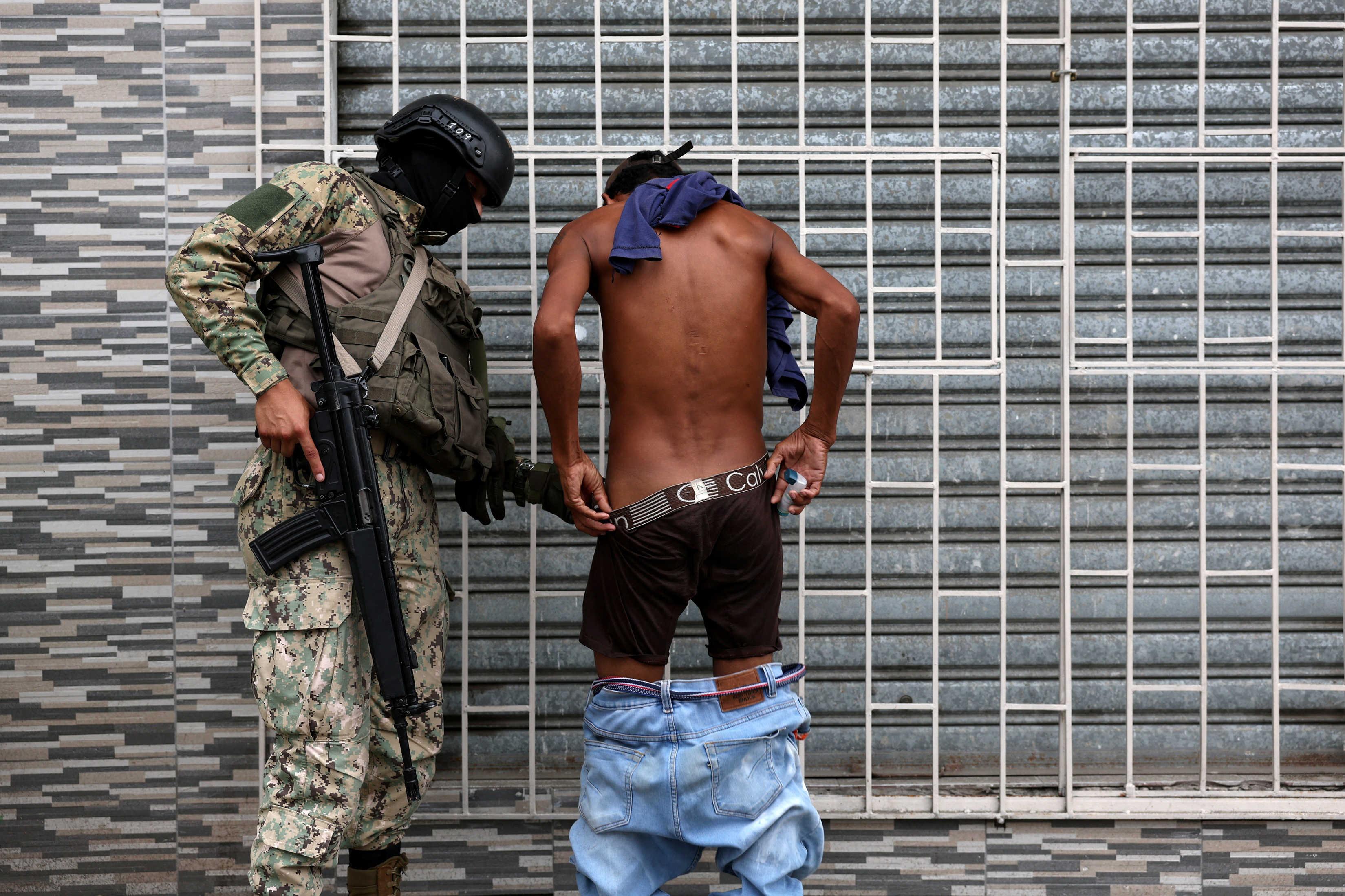 n Ecuadorean armed forces member inspects a person while patrolling at a commercial harbor area, amid the ongoing wave of violence around the nation, in Guayaquil, Ecuador.
